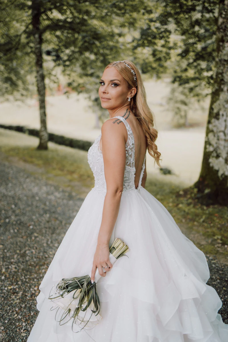 Bride in a ballgown on the tree-lined path