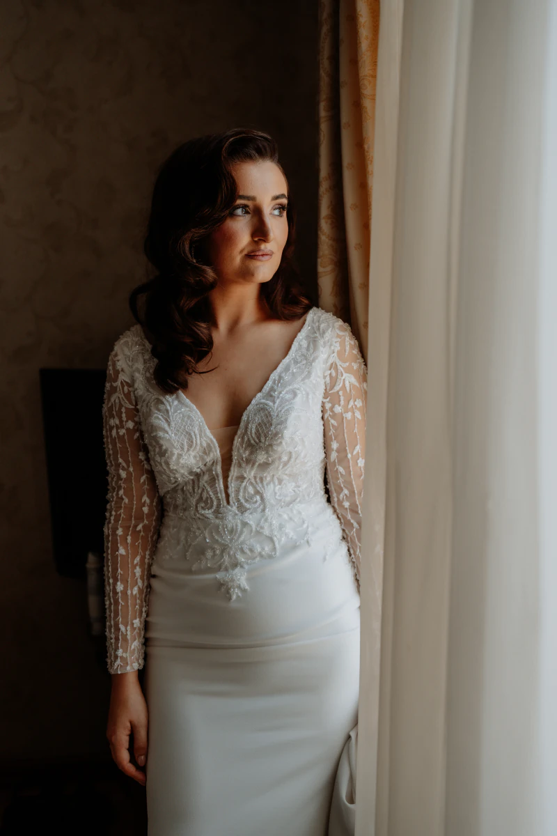 Bride in a lace gown by the window